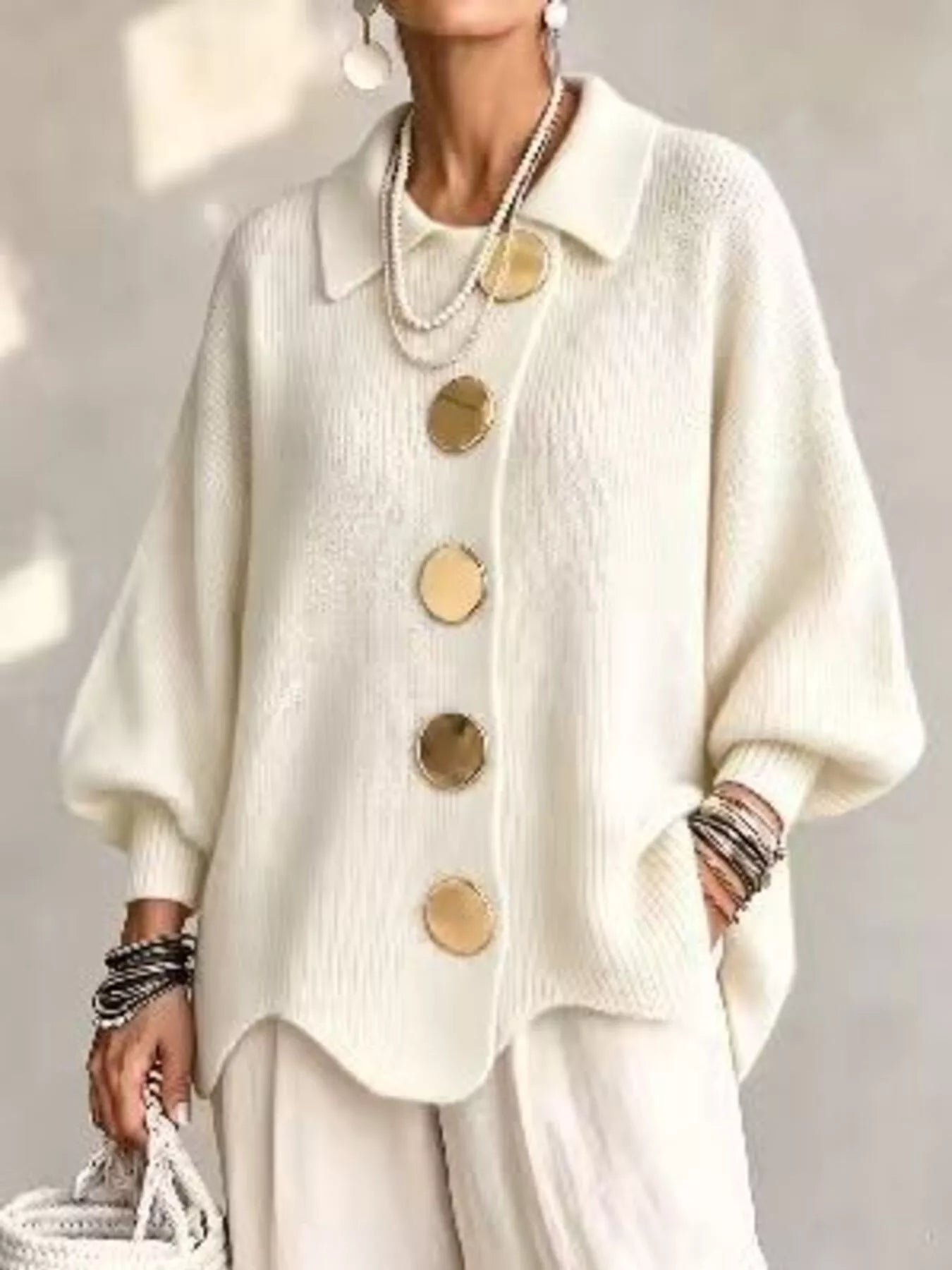 Front view of a cream knit cardigan with large gold buttons and lantern sleeves
