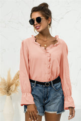 Front view of a peach frill-trim V-neck shirt with flounce sleeves, styled with denim shorts and a black belt