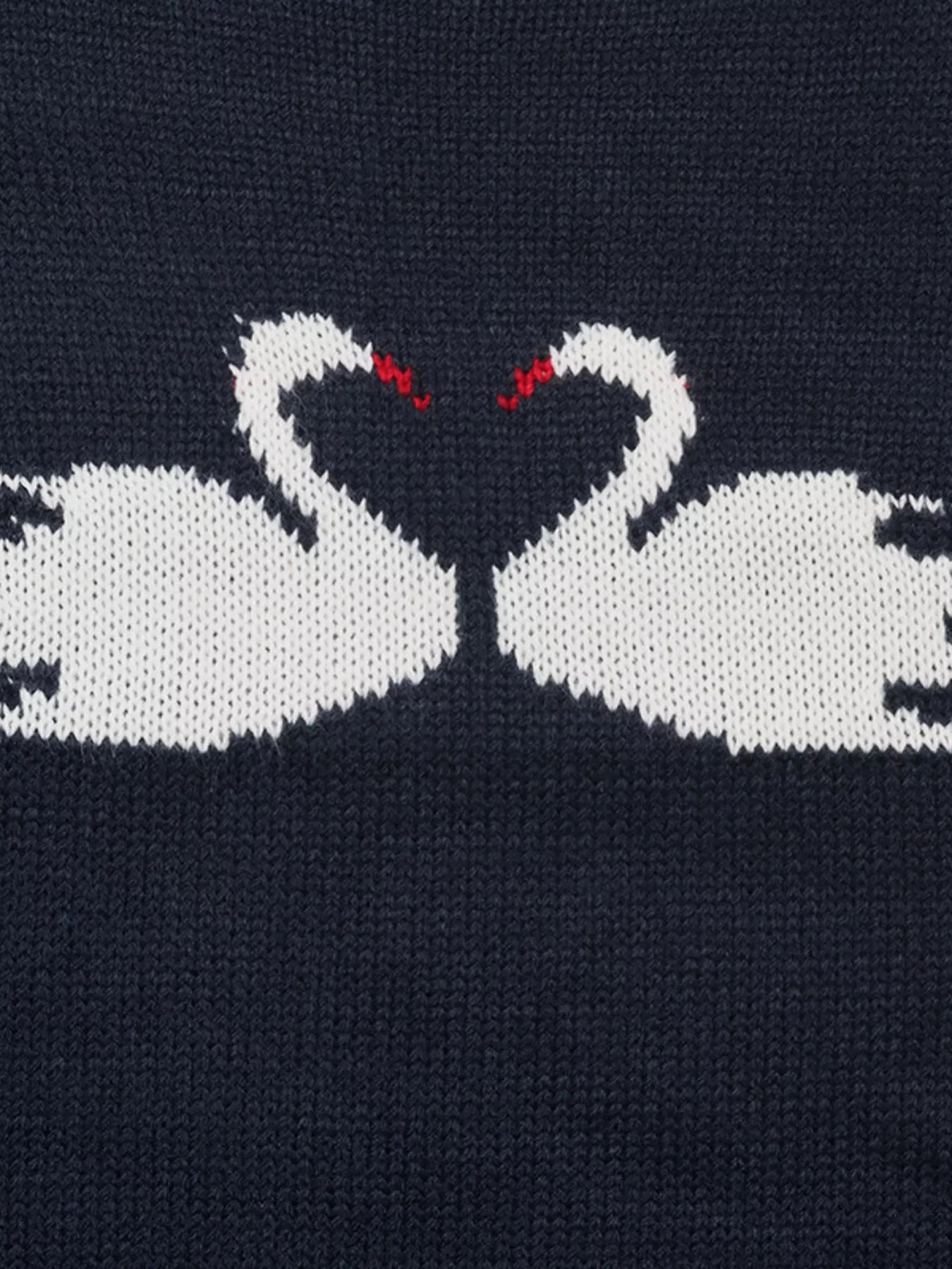 Close up of two facing white swans with red beaks on navy knit fabric
