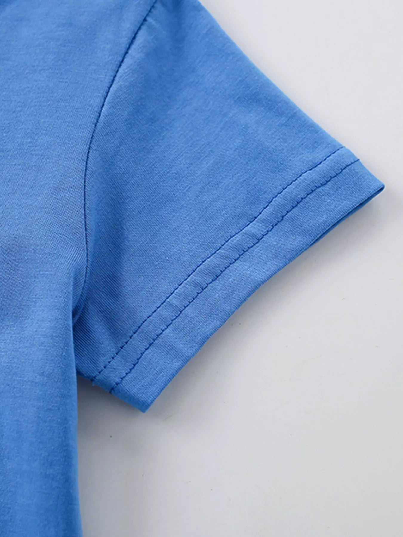 Close-up of blue short sleeve hem stitching showing neat double seams and smooth fabric