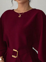 Close view of burgundy round neck blouse showing neckline and gold buckle belt