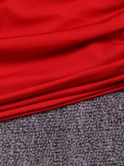 Close detail of red ruched fabric and hem of one shoulder bodycon mini dress