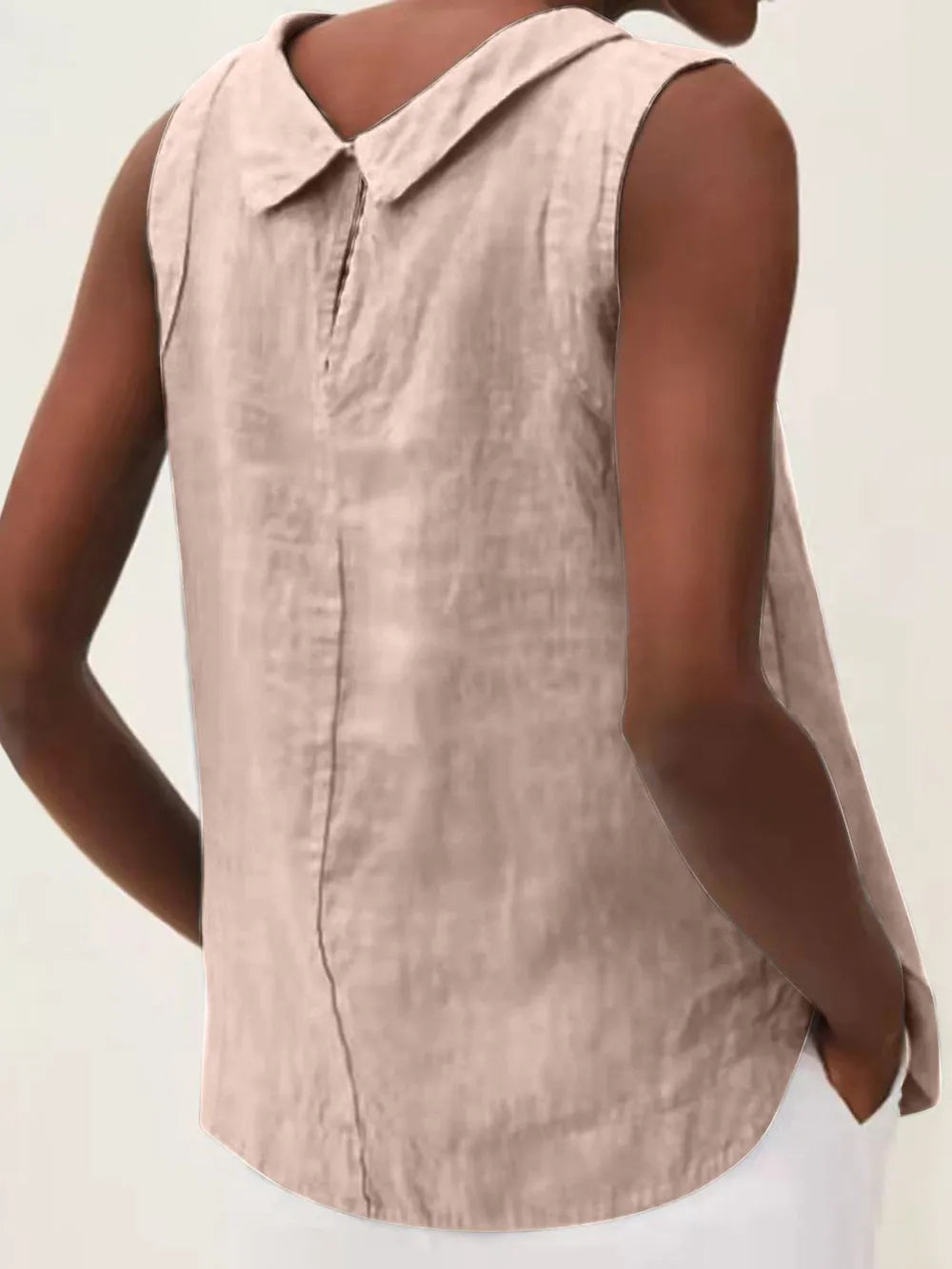 Back view of a sleeveless collared top in a light pink shade with rounded hem.