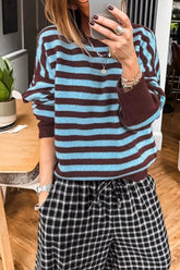 Mirror selfie front view of a blue and brown striped sweater with brown cuffs and check trousers