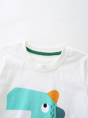 Close-up of white round neckline with green trim above the turquoise cartoon dinosaur graphic