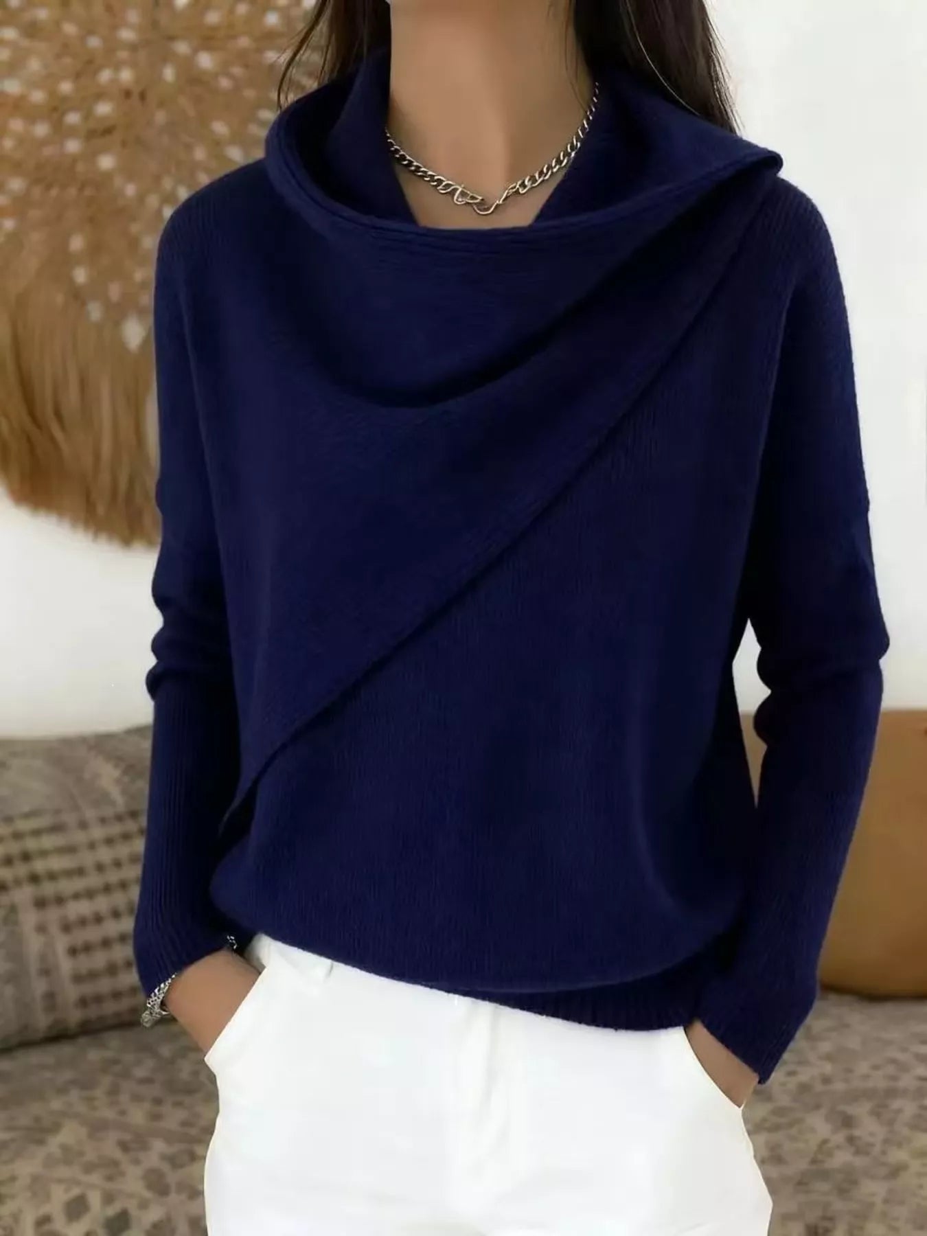 On-model front view of a navy cowl neck sweater with a draped asymmetric collar and long sleeves