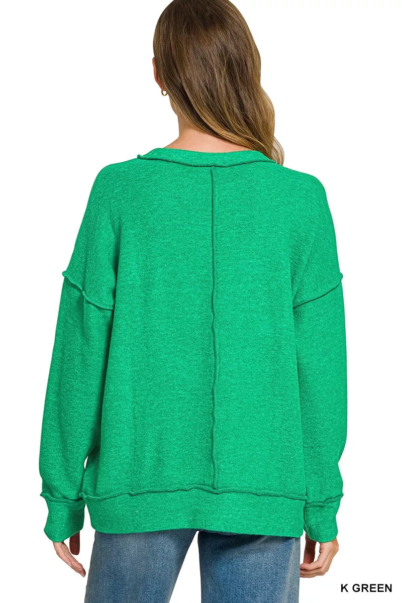 Back view of bright green drop shoulder sweater with centre seam and ribbed hem