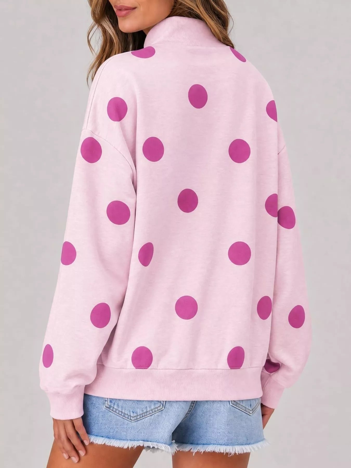Back view of pink mock neck oversized sweatshirt with large magenta polka dots on model