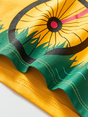 Close-up of yellow children's t-shirt hem with bicycle wheel and green grass print