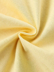 Close up of gathered pale yellow fabric showing the plain knit texture of a children's tee