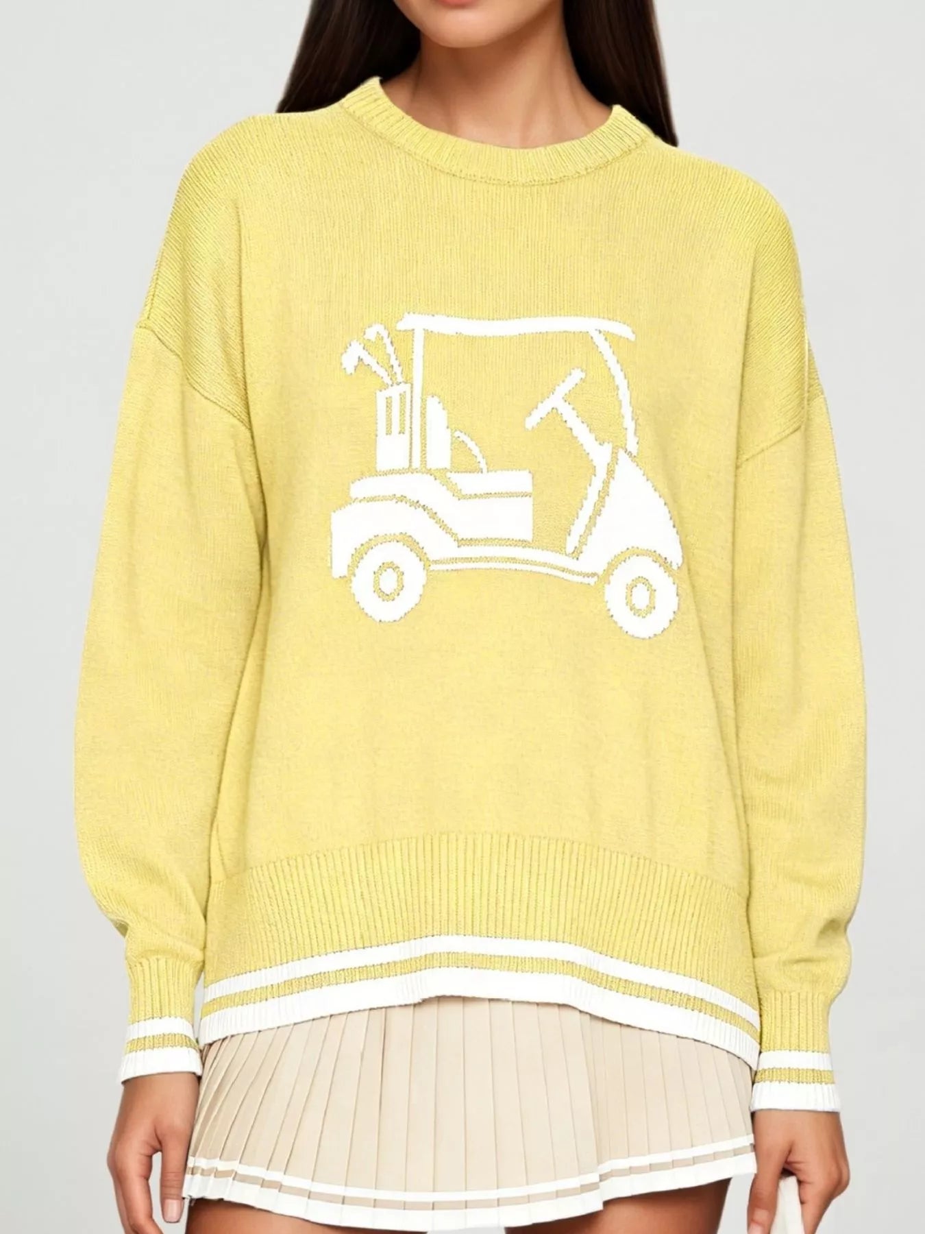 Front view of a pale yellow dropped shoulder sweater with a white golf cart graphic and striped trim.