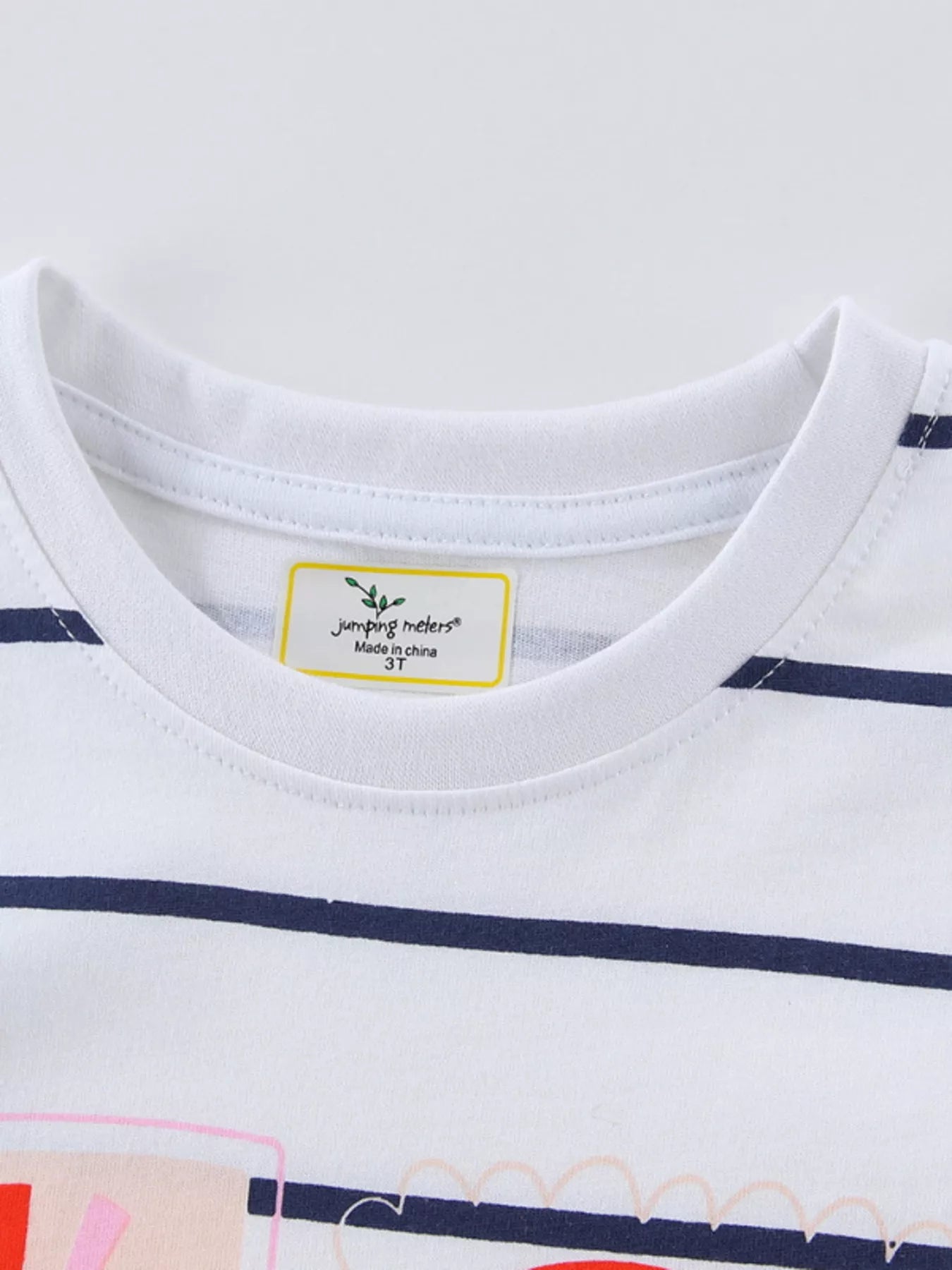 Detail view of the round neckline and care label inside a children's white navy striped t-shirt