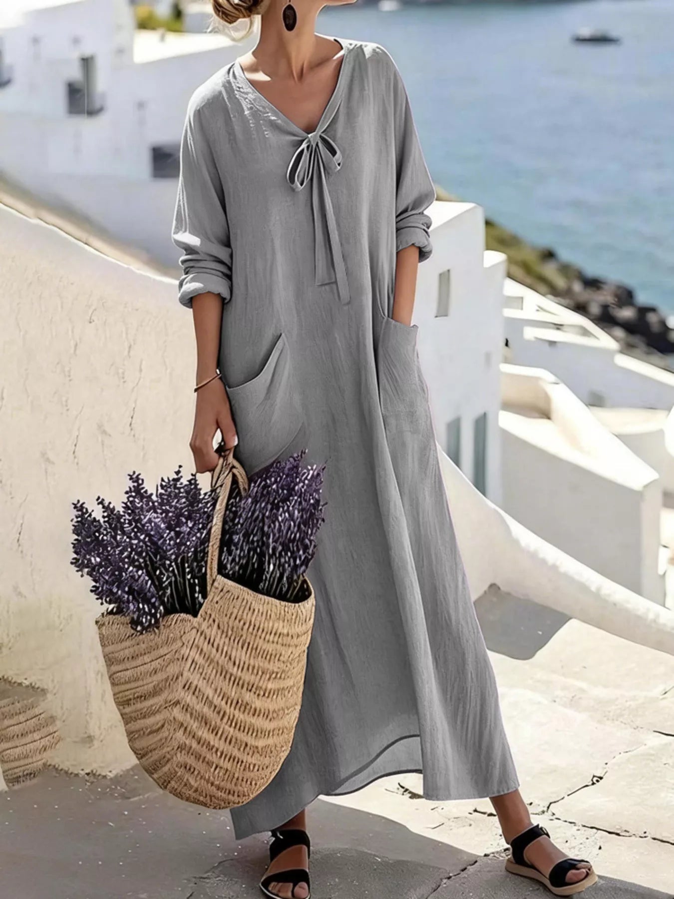 Model wearing grey long sleeve loose maxi dress outdoors, full view with large pockets and tie neck