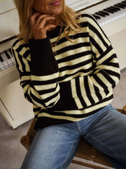 Close seated on-model view of a black and yellow striped crew neck sweater