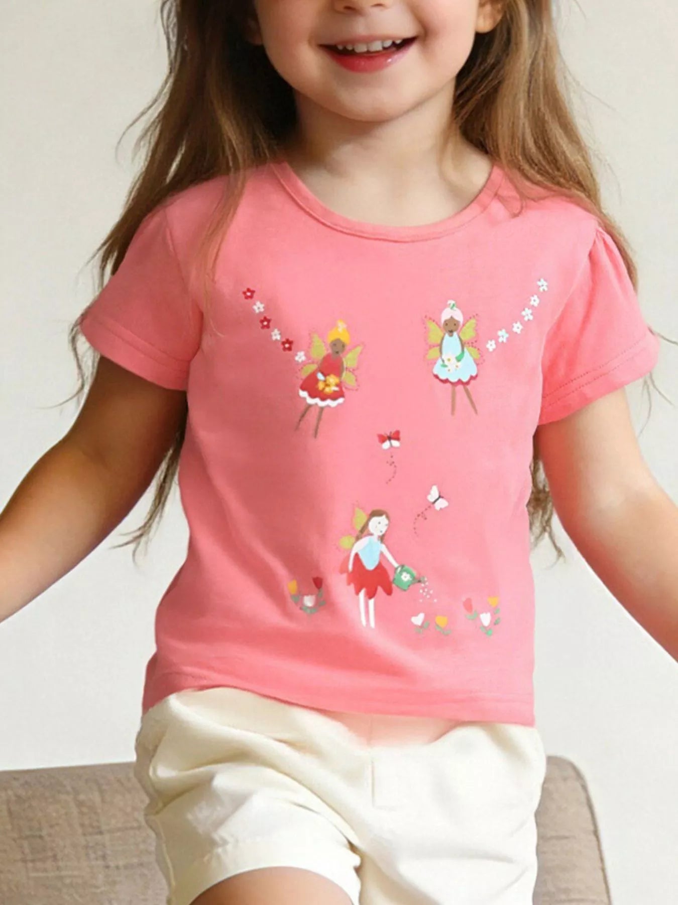 Children's coral short-sleeve T-shirt featuring a fairy print design.