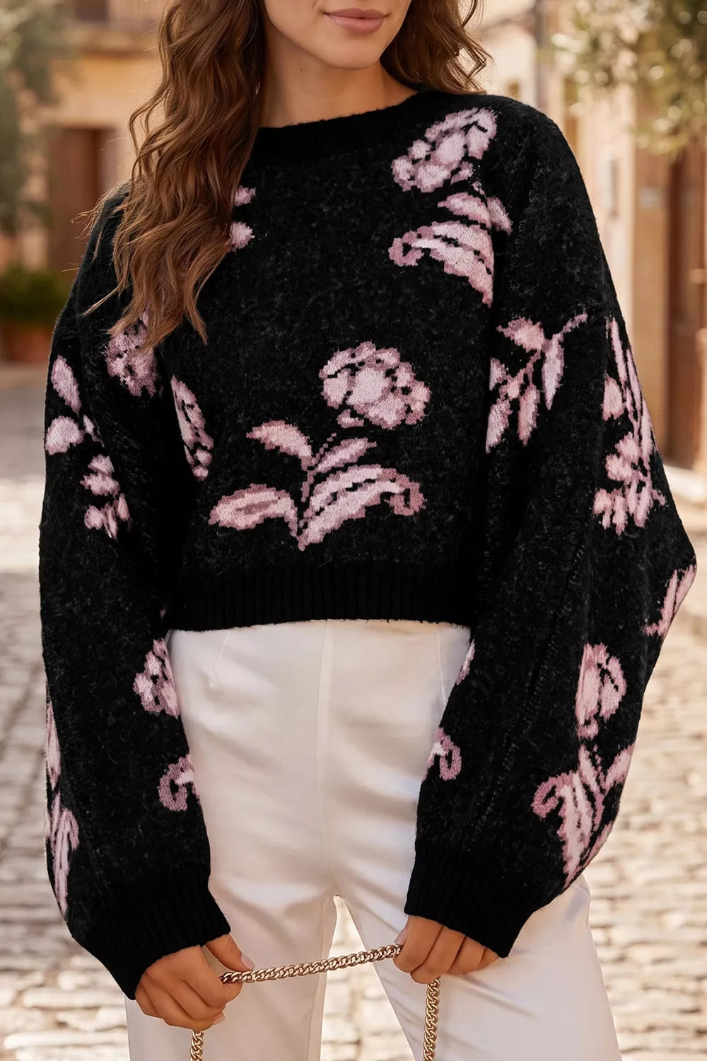 Black floral pattern pullover sweater with pink flowers and puff sleeves, front view on model outdoors