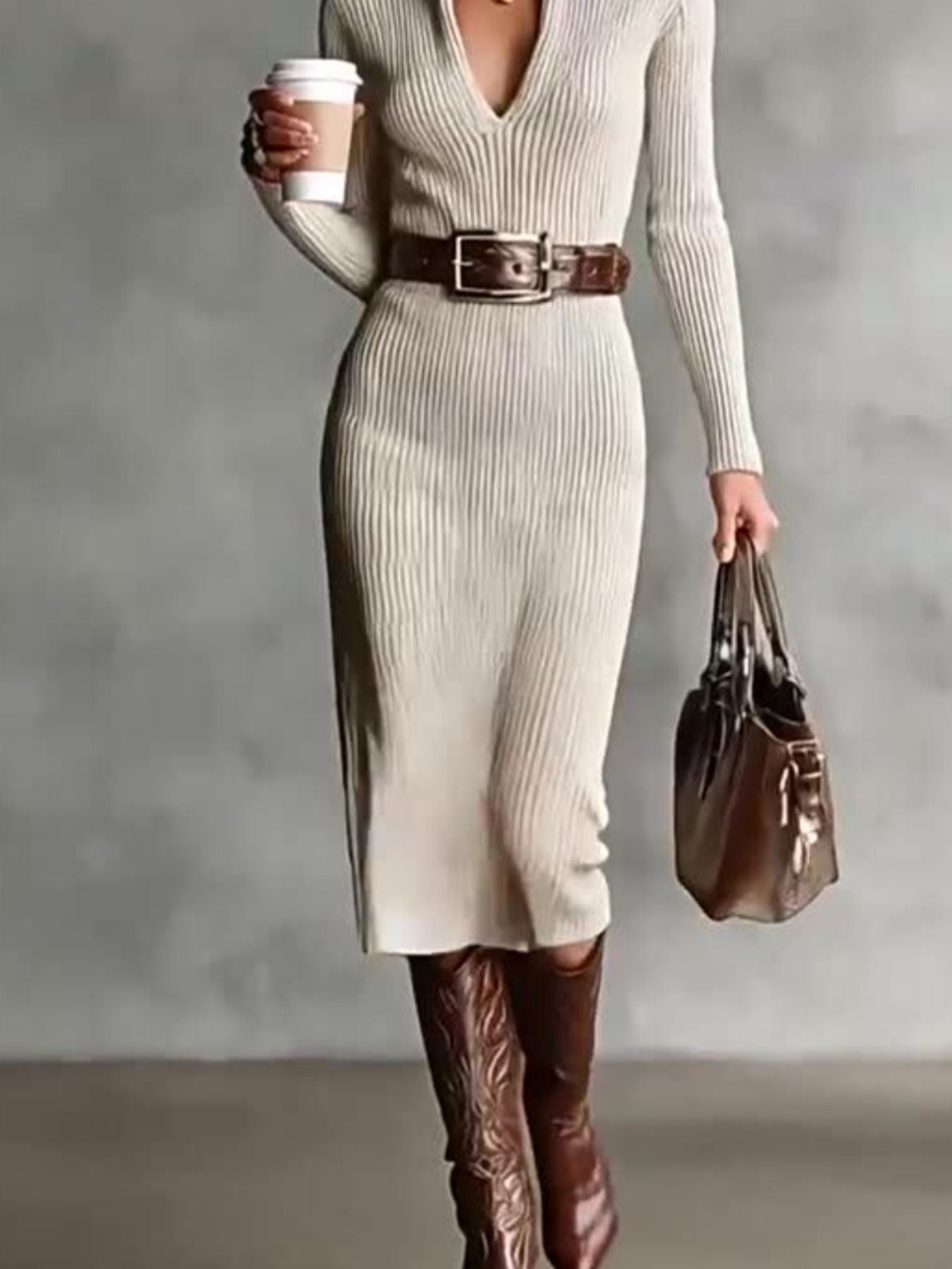 Lower front view of a beige ribbed knit turtleneck bodycon sweater dress with boots and a bag