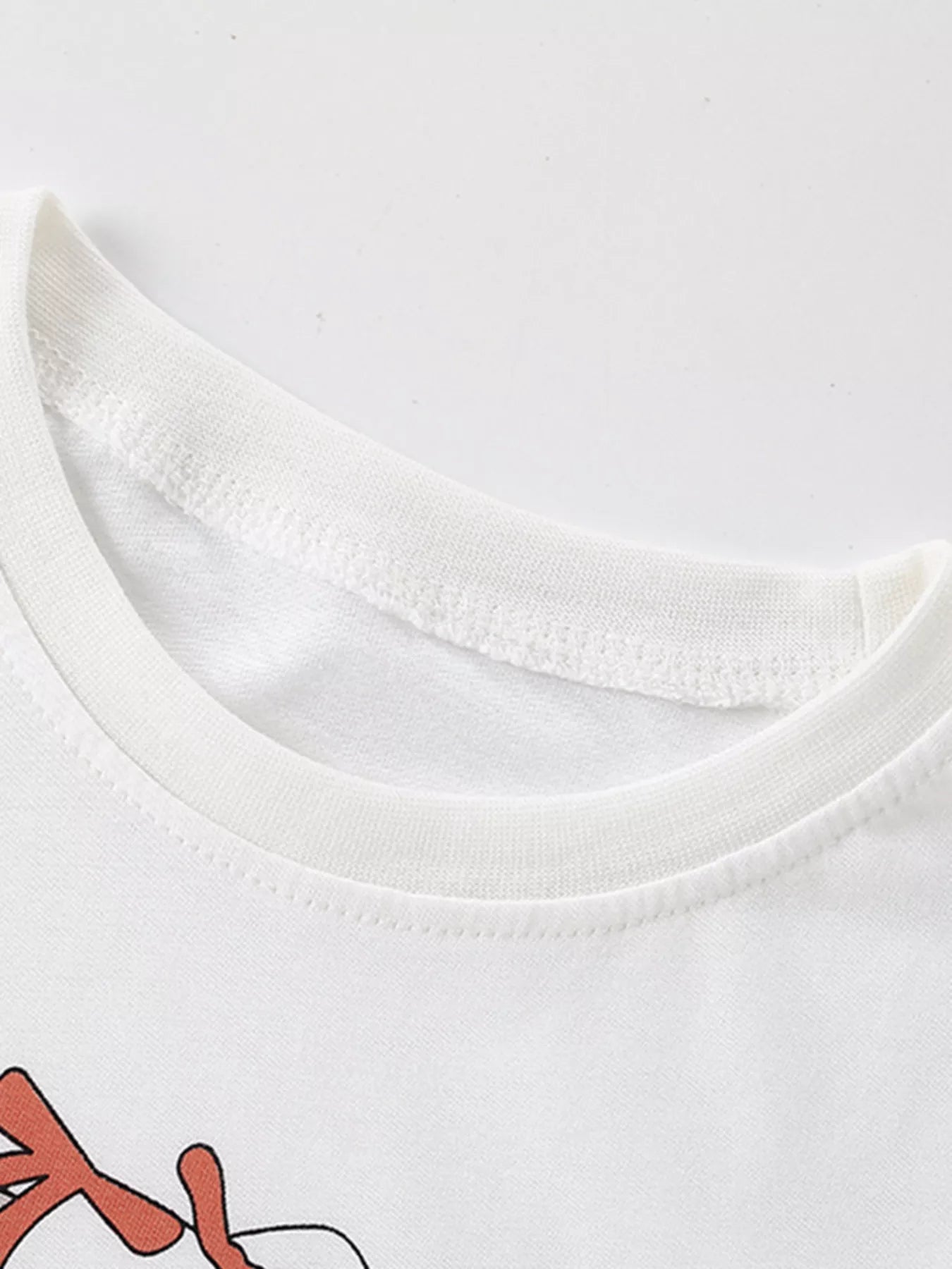 Close-up of white children's t-shirt ribbed crew neckline and stitching, with bunny graphic below