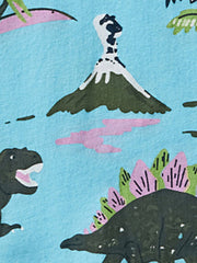 Close-up print detail showing dinosaurs and a volcano on pastel blue children's tee fabric