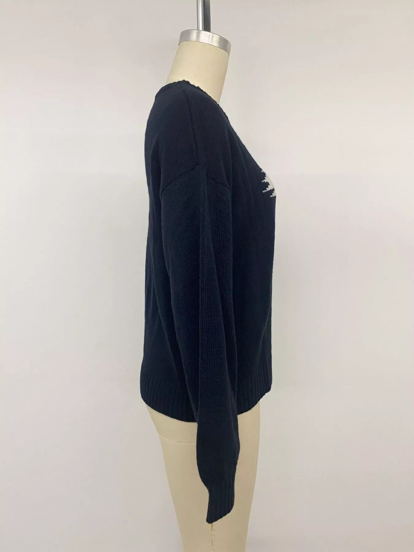 Side view on a mannequin of a plain navy sweater with long sleeves and ribbed hem