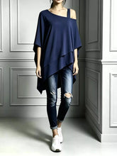 Navy asymmetrical-neck short-sleeve tunic top with a draped, uneven hem, modeled with jeans and sneakers