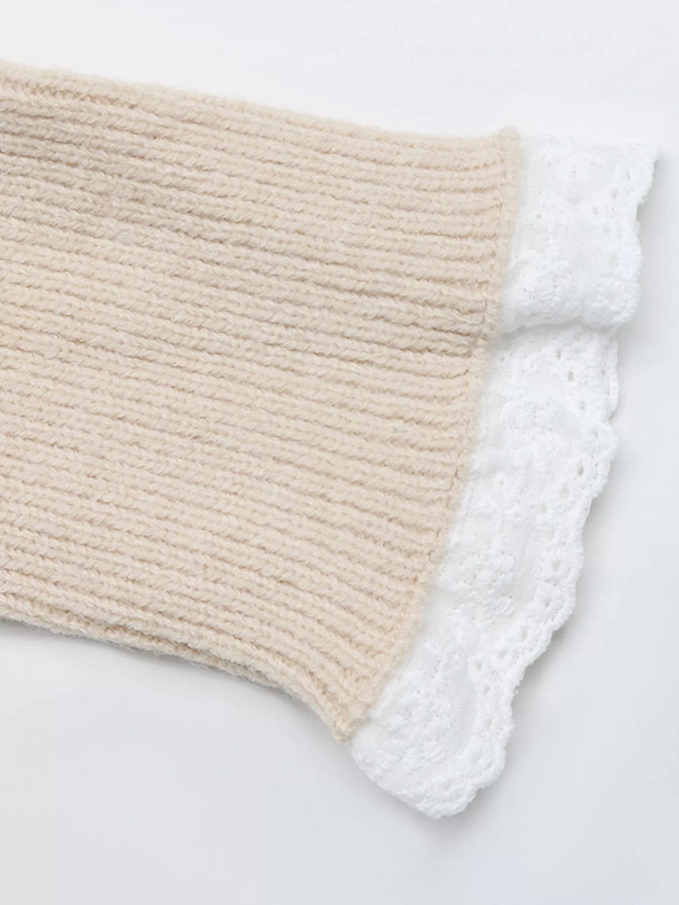 Close up of beige sweater dress cuff with ribbed knit and white lace edge trim