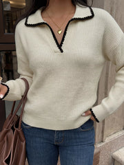 Front view of a cream ribbed sweater with black scalloped trim on collar and cuffs