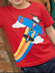 Red children's short sleeve t-shirt shown worn, with blue airplane, clouds and rainbow trail graphic