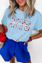 Women's light blue relaxed T-shirt featuring floral-print “1776” lettering and white America script detail.