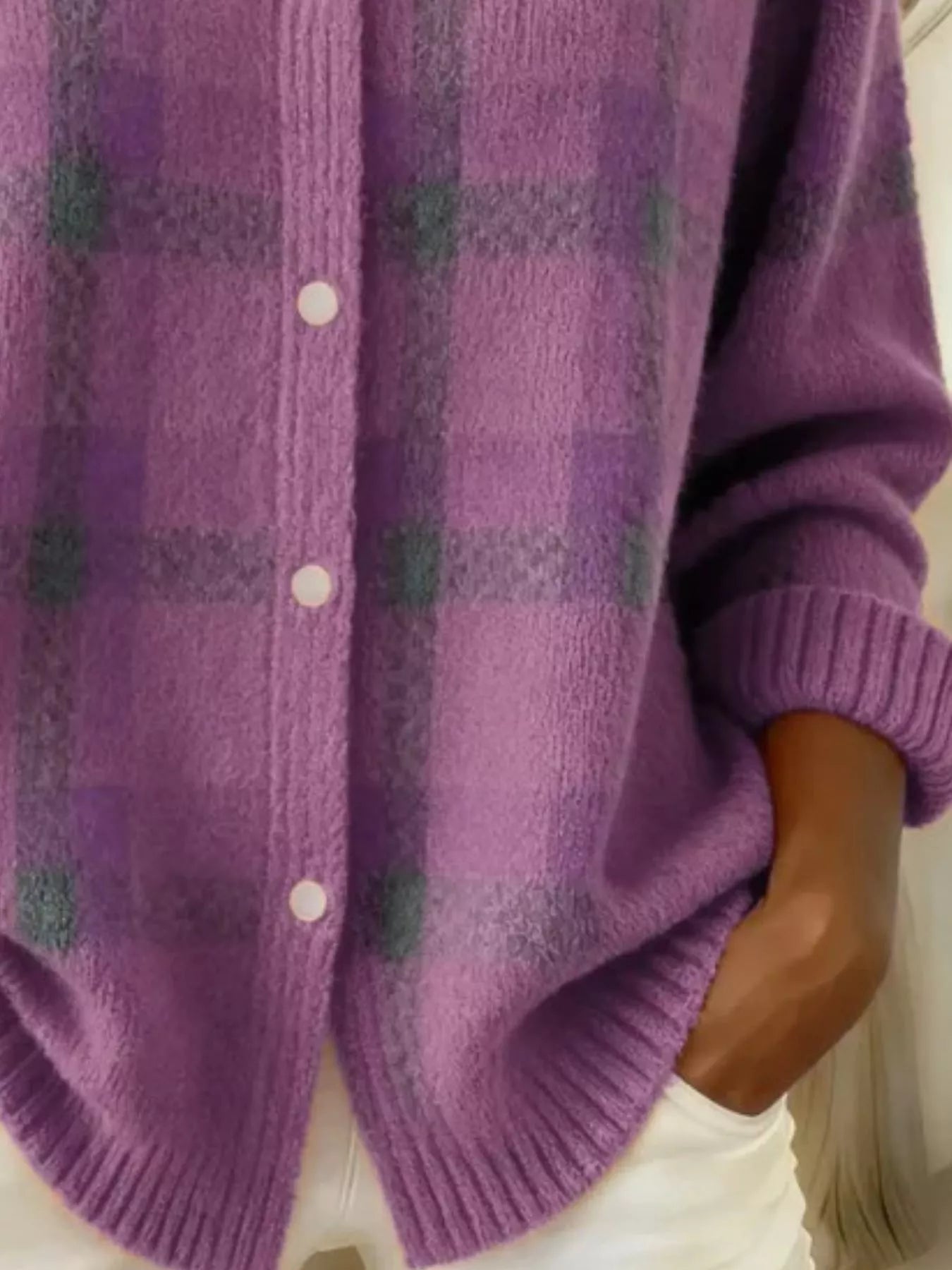 Close-up of the lower front and ribbed hem of a light purple plaid knit cardigan