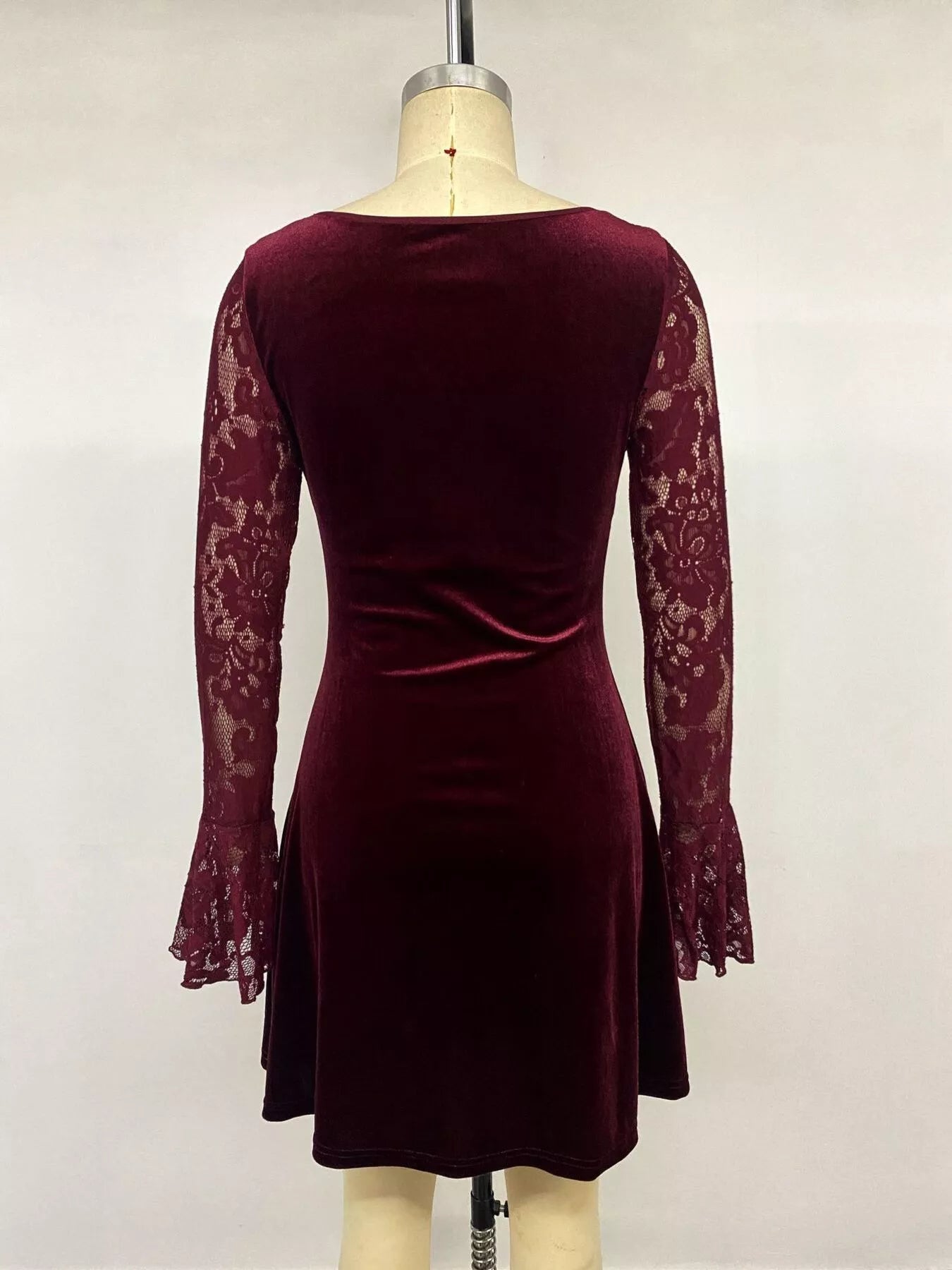 Back view of burgundy lace mini dress on mannequin with velvet skirt and lace sleeves