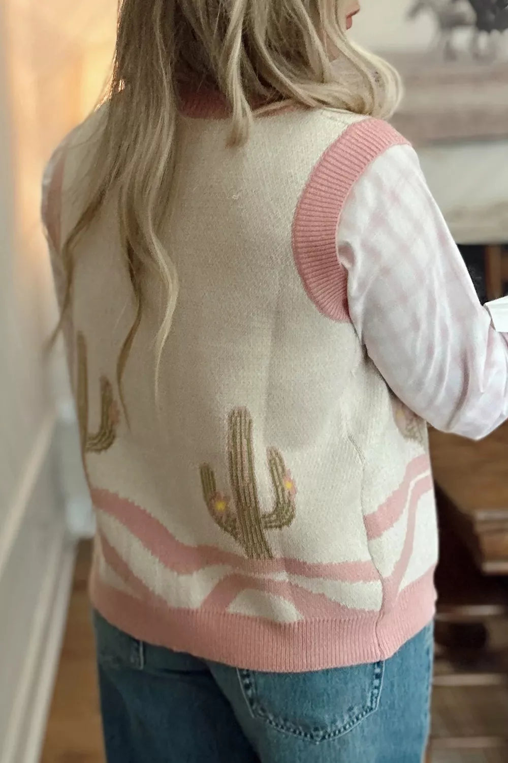 On-model back view of the cream cactus sweater vest with pink trim over a pink check shirt
