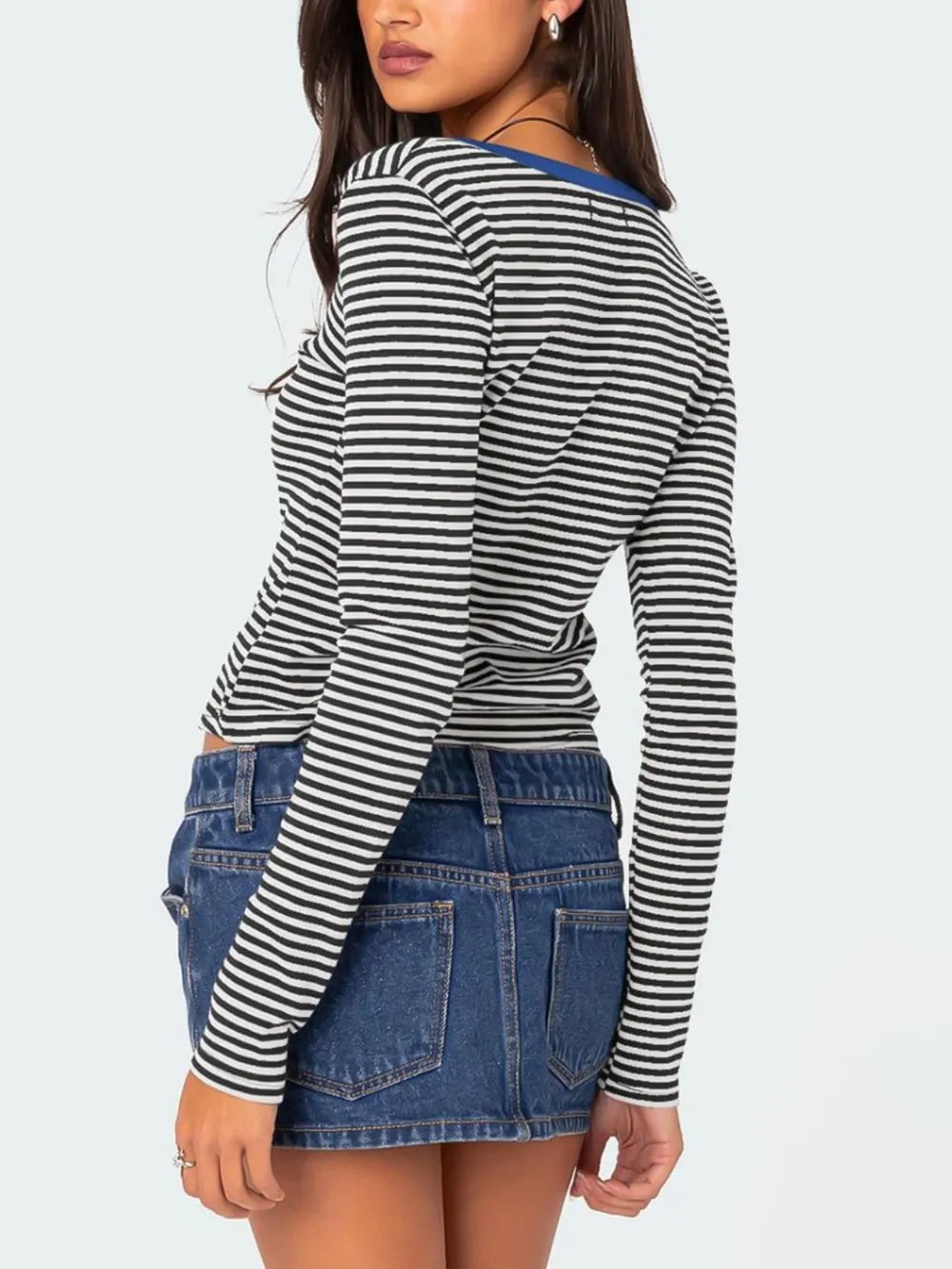 Back view of black and white striped long sleeve t shirt with royal blue neckline trim worn on model