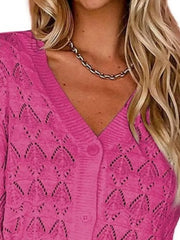 Close view of bright pink openwork knit cardigan showing V neckline and button front.