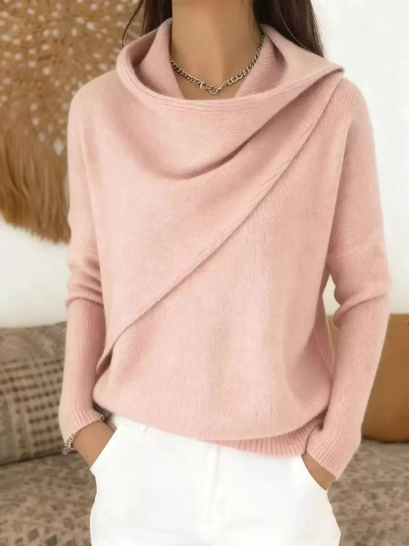 On-model front view of a pale pink cowl neck sweater with a draped asymmetric collar and long sleeves