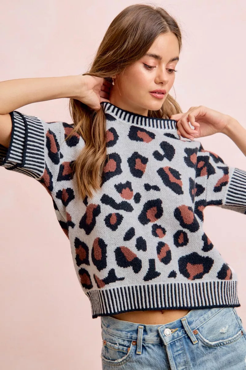 Front view of a light gray leopard print knit top with striped collar and cuffs.