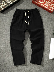 Men's black loose-fit pants with a drawstring waist and pockets.