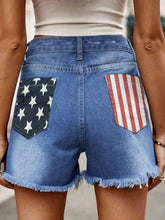 Women's denim shorts with an American flag pattern, pockets, and raw hems.