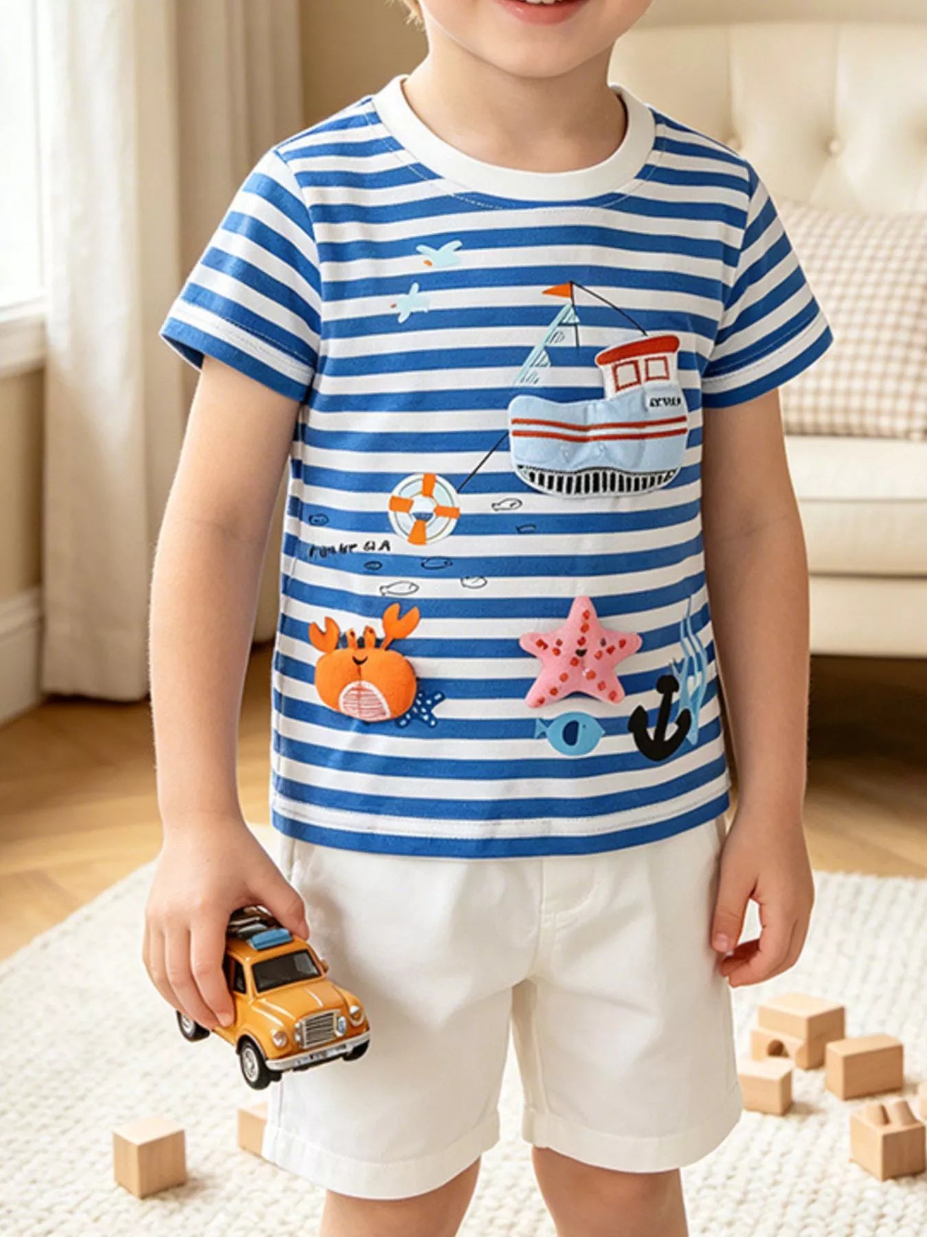 Front view of a children's blue and white striped short sleeve tee with nautical appliques
