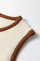 Close up detail of a beige sweater vest armhole with brown contrast trim and knit texture