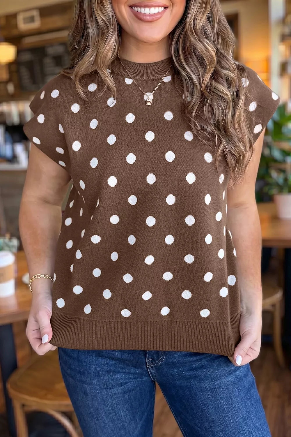 Front view of a brown sweater with white polka dots, short sleeves, and ribbed hem