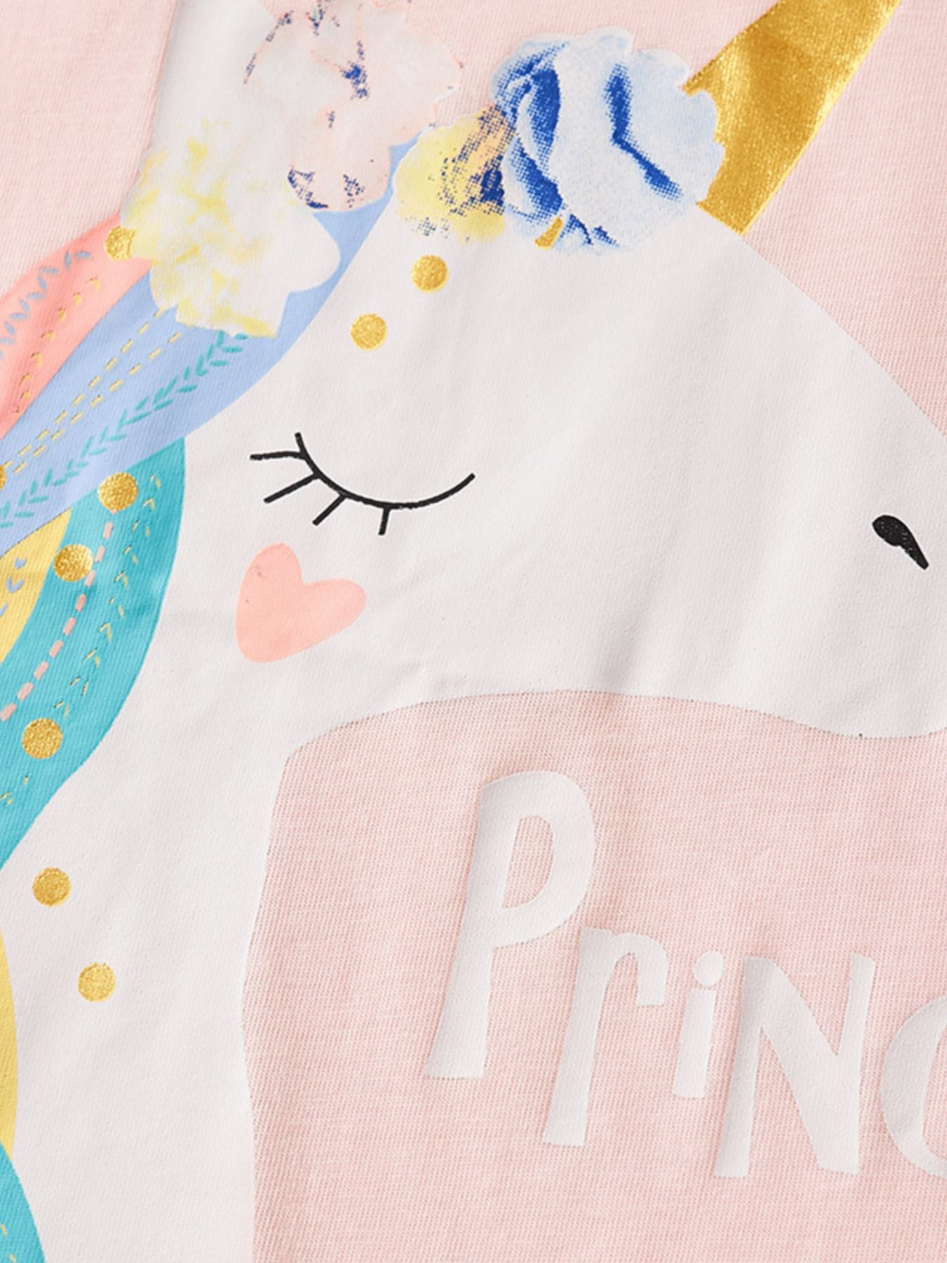Close-up of the white unicorn face with gold horn and floral crown on pink fabric