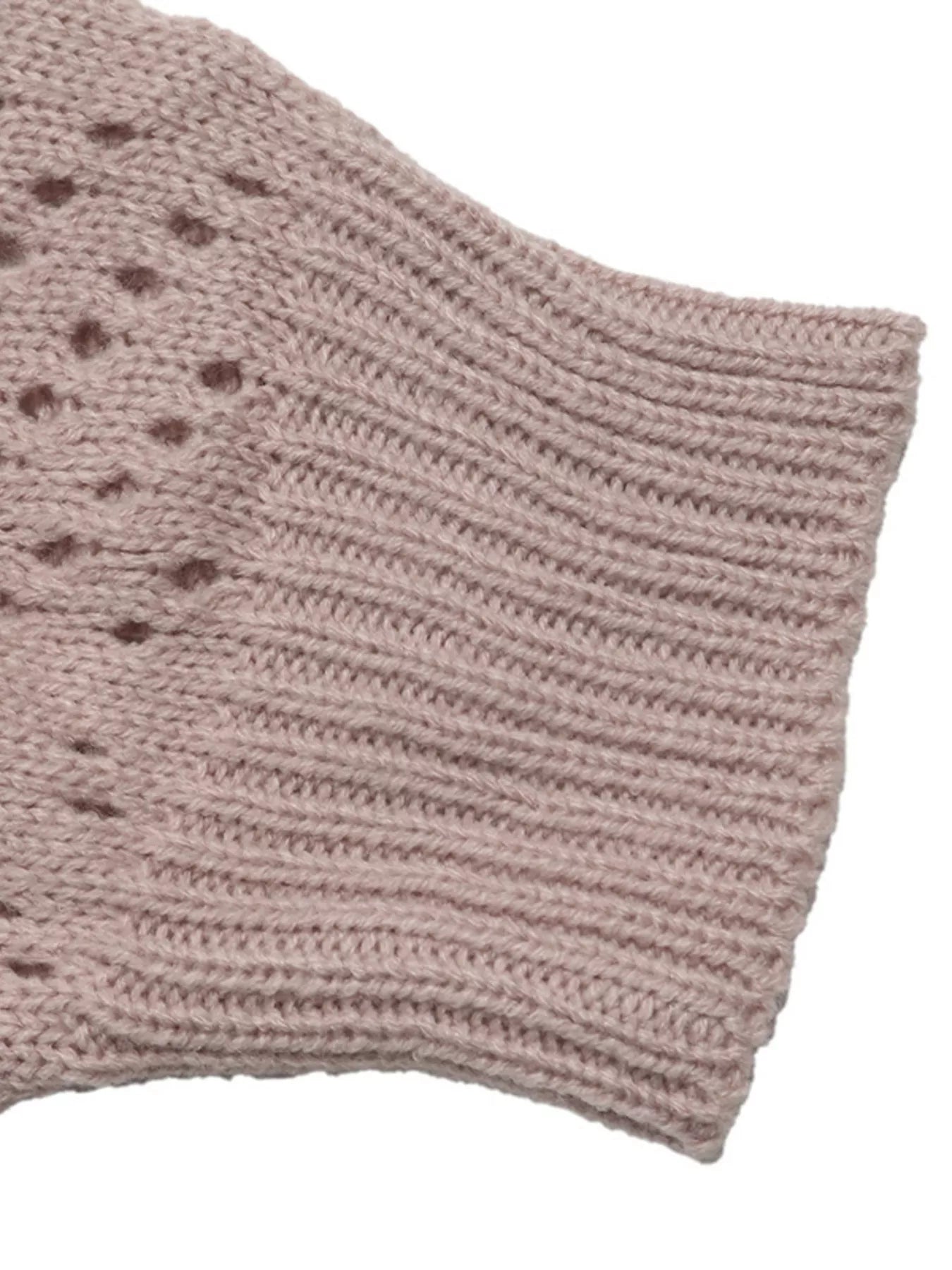 Close up of a pink openwork sleeve with ribbed cuff and dotted knit pattern