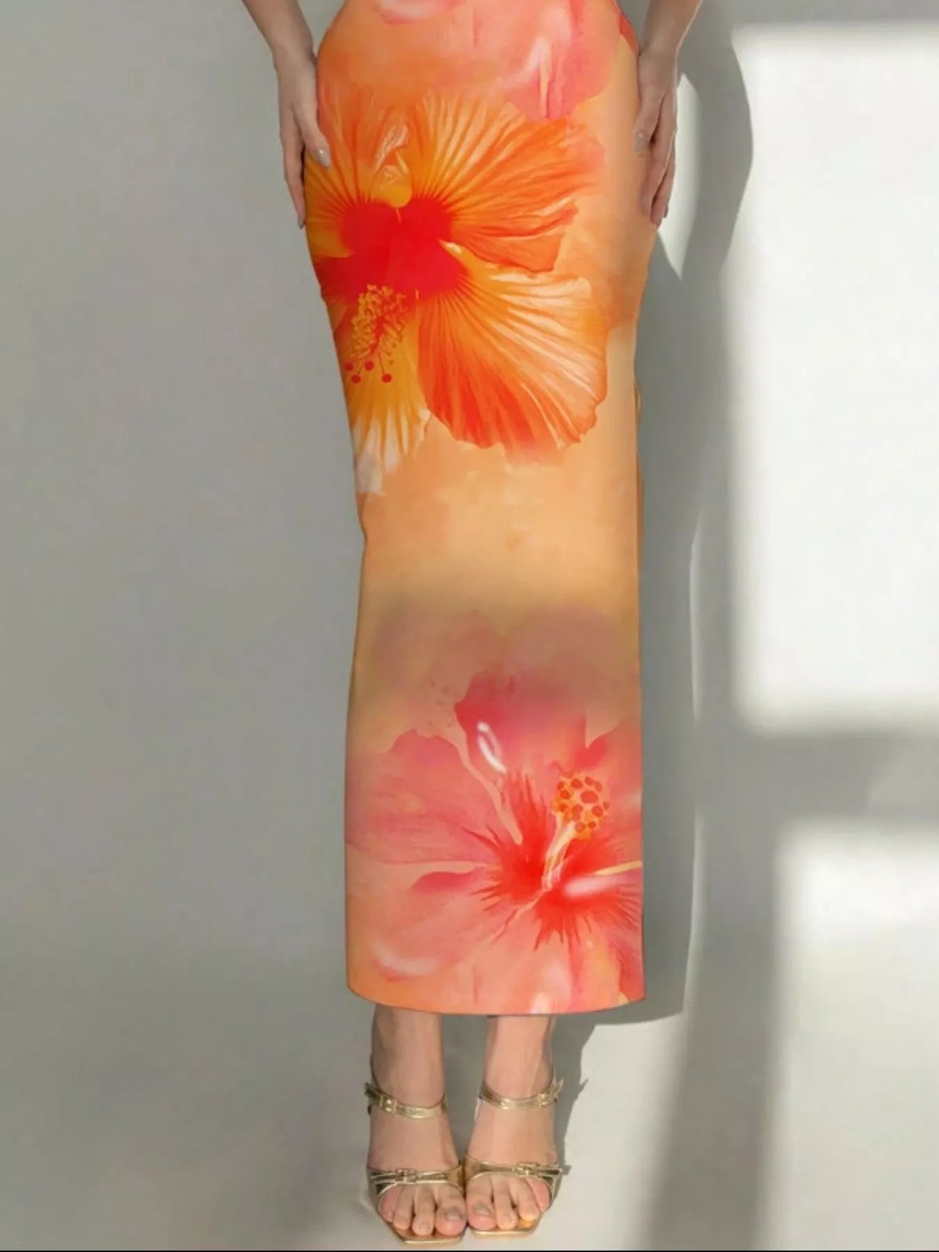 Lower view of tangerine tropical flower print bodycon tube dress showing hibiscus flowers and hem