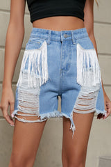 Women's distressed denim shorts with fringe trim and pockets.