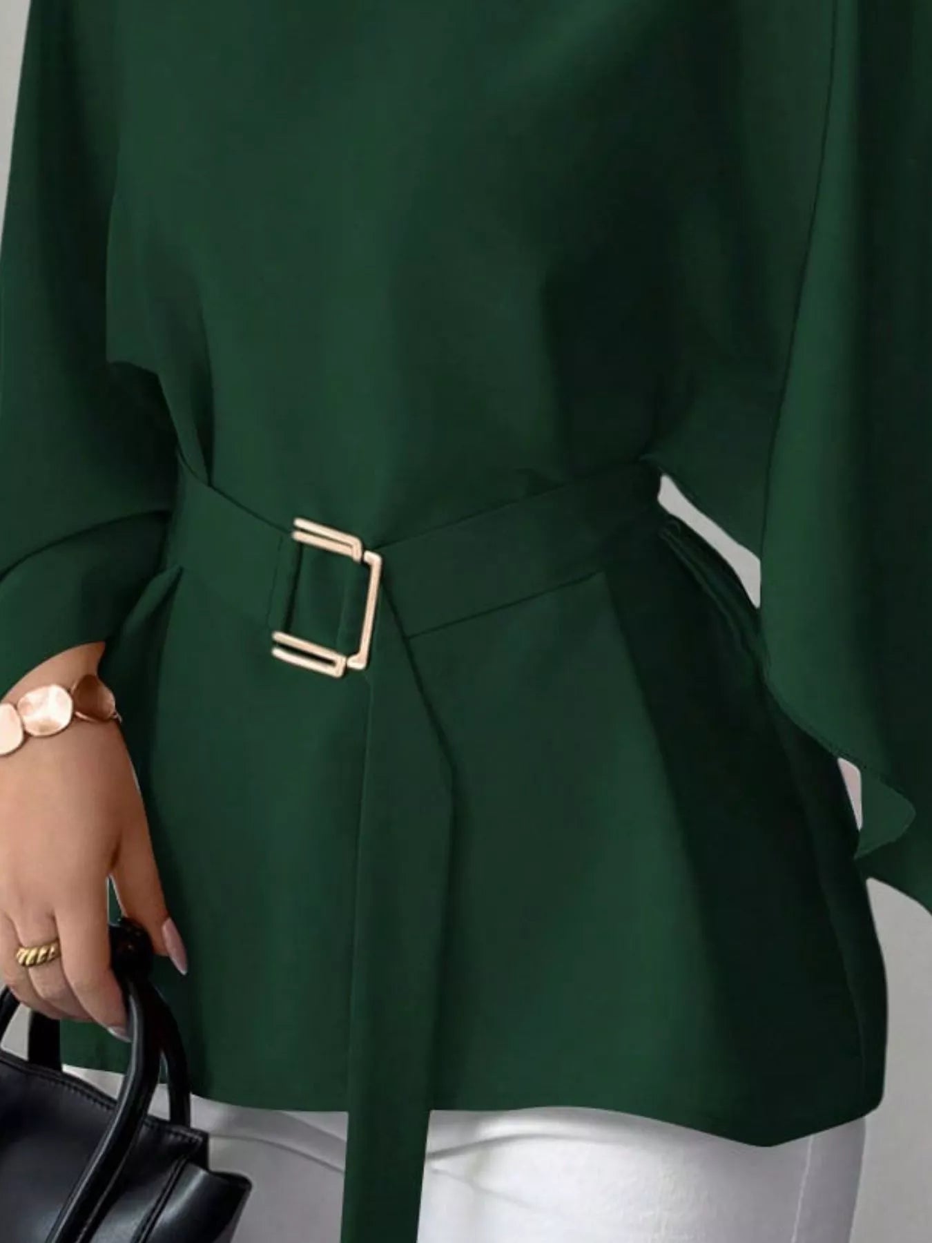 Close detail of dark green batwing sleeve blouse gold buckle belt and flared hem