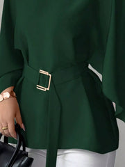 Close detail of dark green batwing sleeve blouse gold buckle belt and flared hem