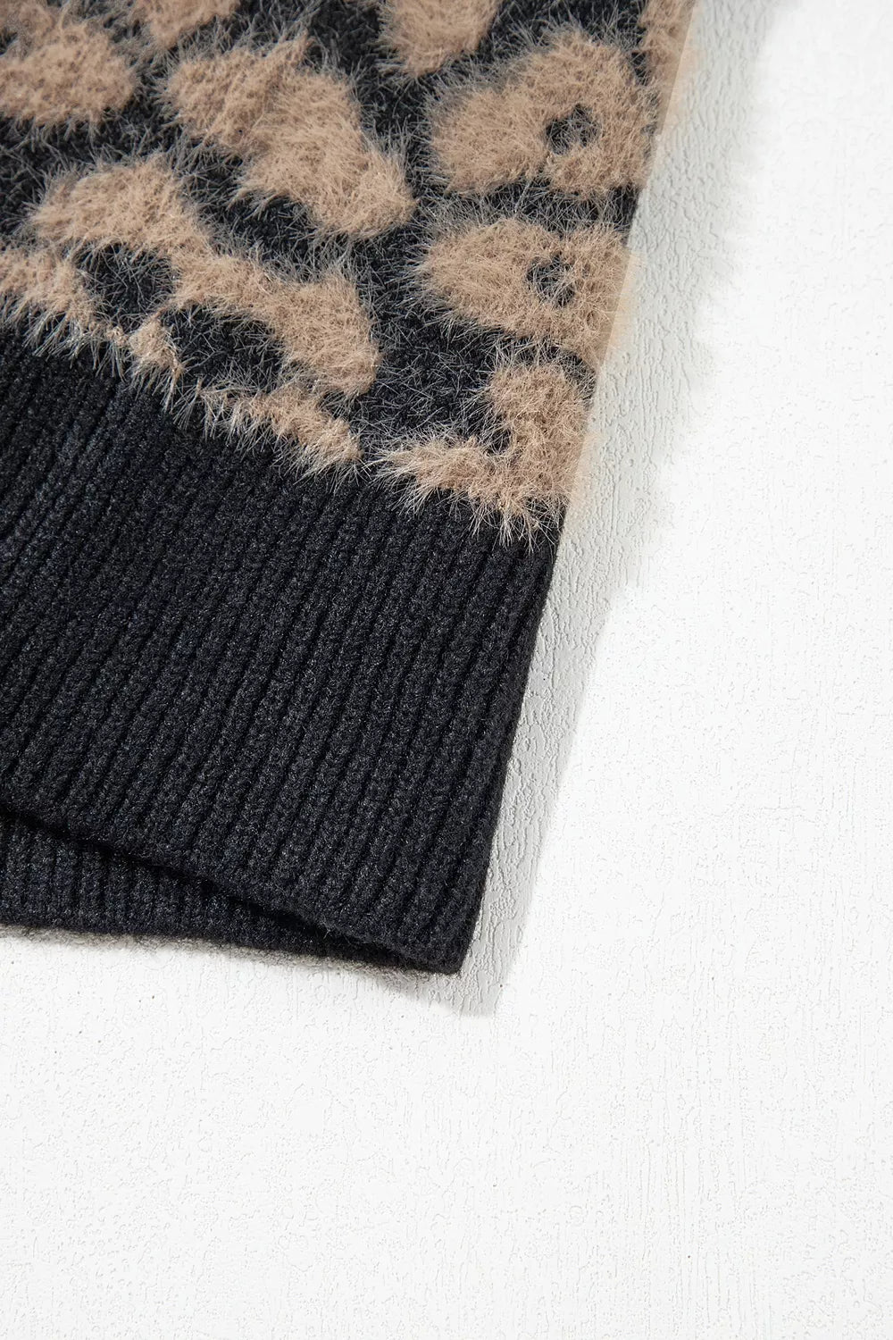 Close up of black ribbed hem below tan and black leopard print knit.