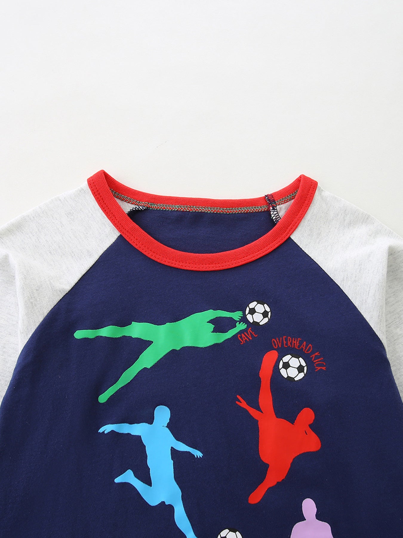 Close-up of the red round neckline and soccer player graphic on the dark navy tee