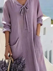 Cropped front view of light purple long sleeve loose maxi dress, showing tie neck and large pockets